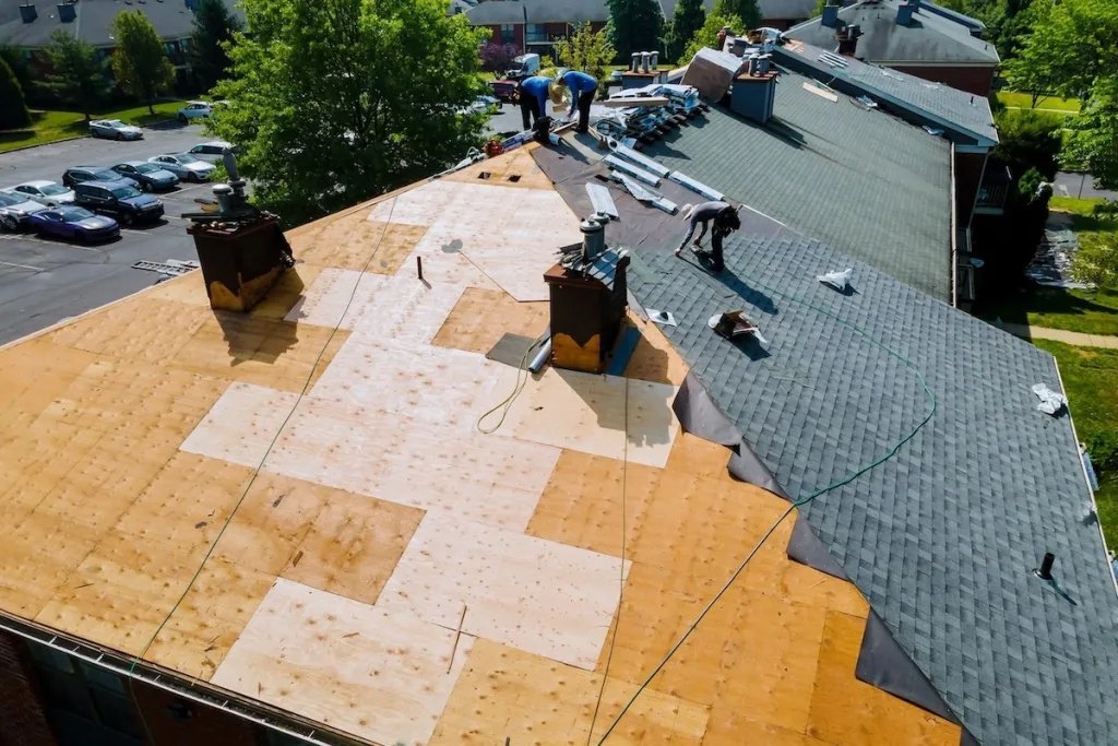 Aerial view of roofers working on a large residential roof replacement project,