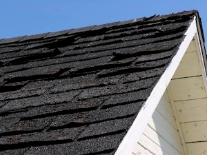 Close-up of an old, weathered roof with visibly damaged and curled shingles, indicative of aging and the need for replacement.